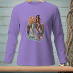 Two mermaids with colorful tails sit on a dock, one holding flowers, the other a drink.