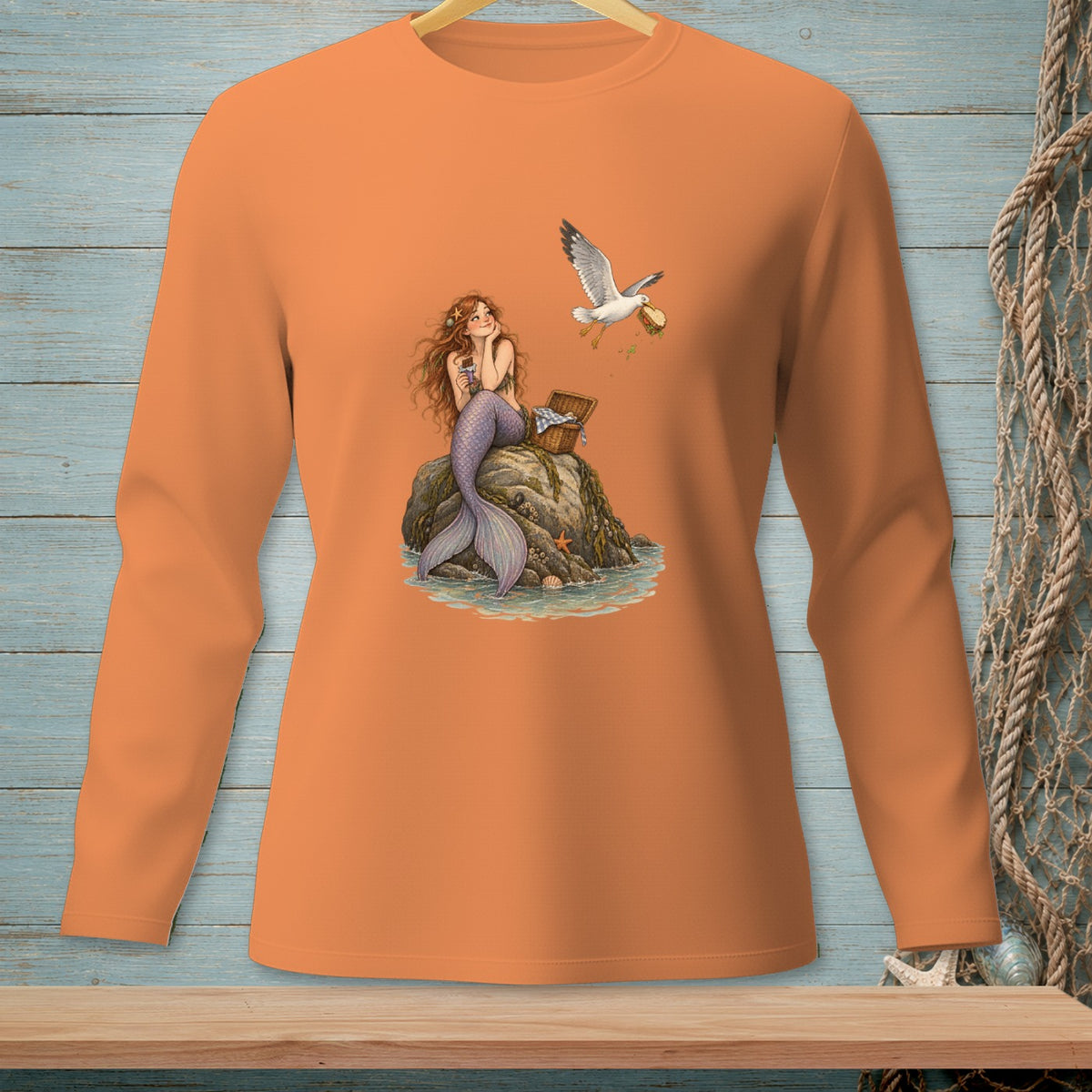 Mermaid sitting on rock with picnic basket; seagull flying away with food.