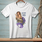 White t-shirt with a graphic of a mermaid holding a drink, resting on a rock.