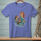 Two mermaids on a rock with one holding a shell to her ear.
