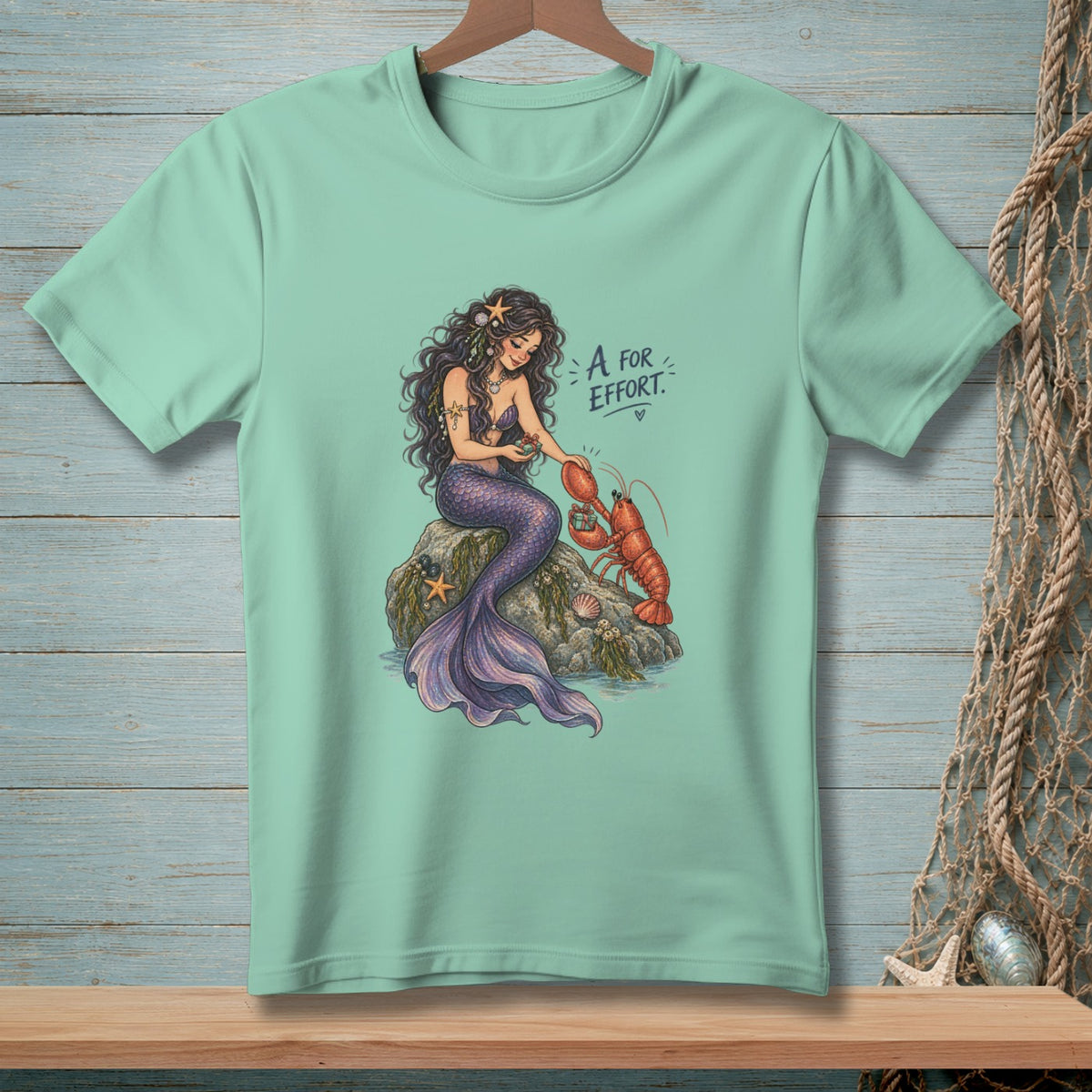 Mermaid with lobster on rock, text "A FOR EFFORT." and a heart.