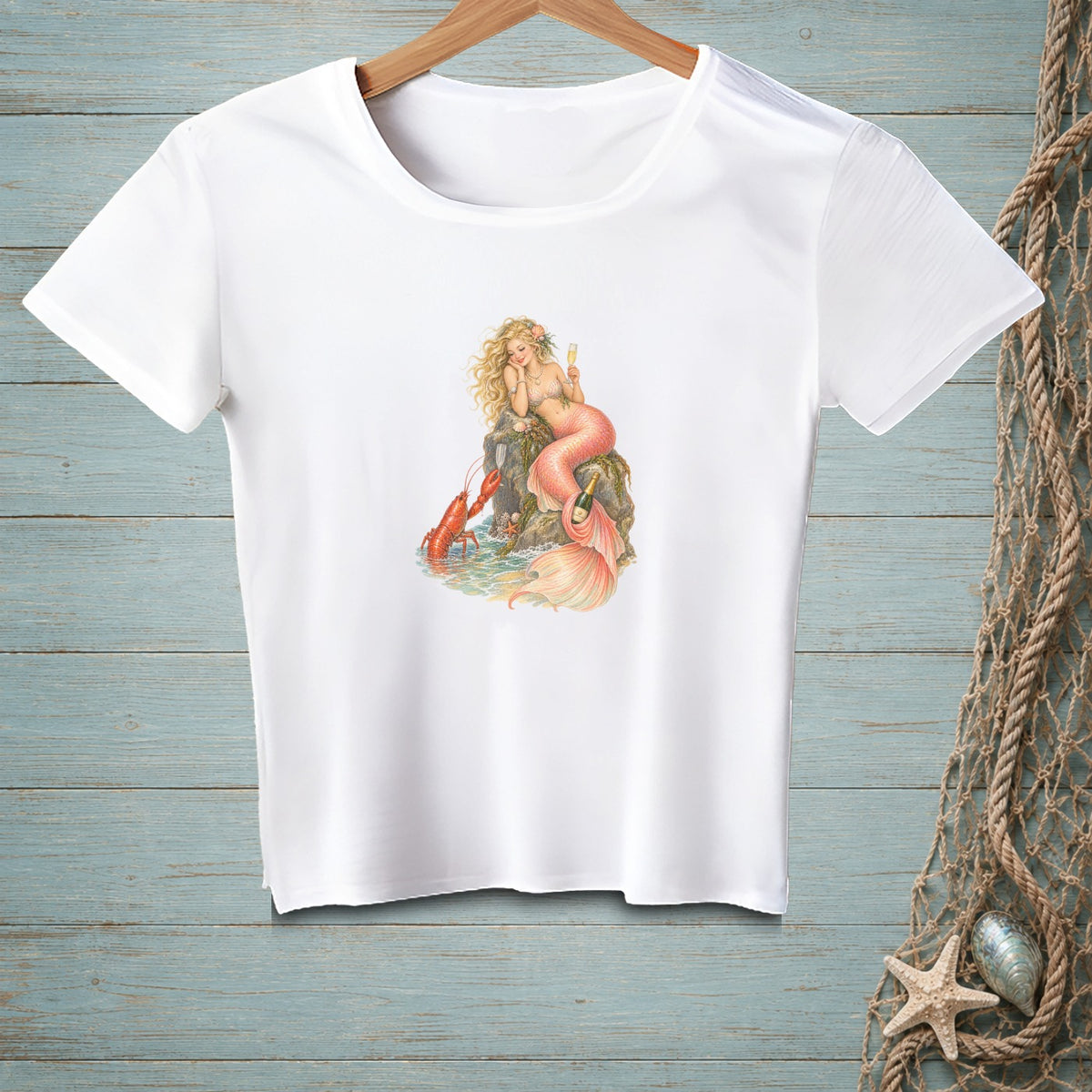 White t-shirt with a graphic of a mermaid and a lobster by the sea.
