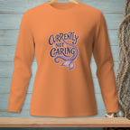 Orange long-sleeve shirt with "Currently Not Caring" and mermaid tail graphic.