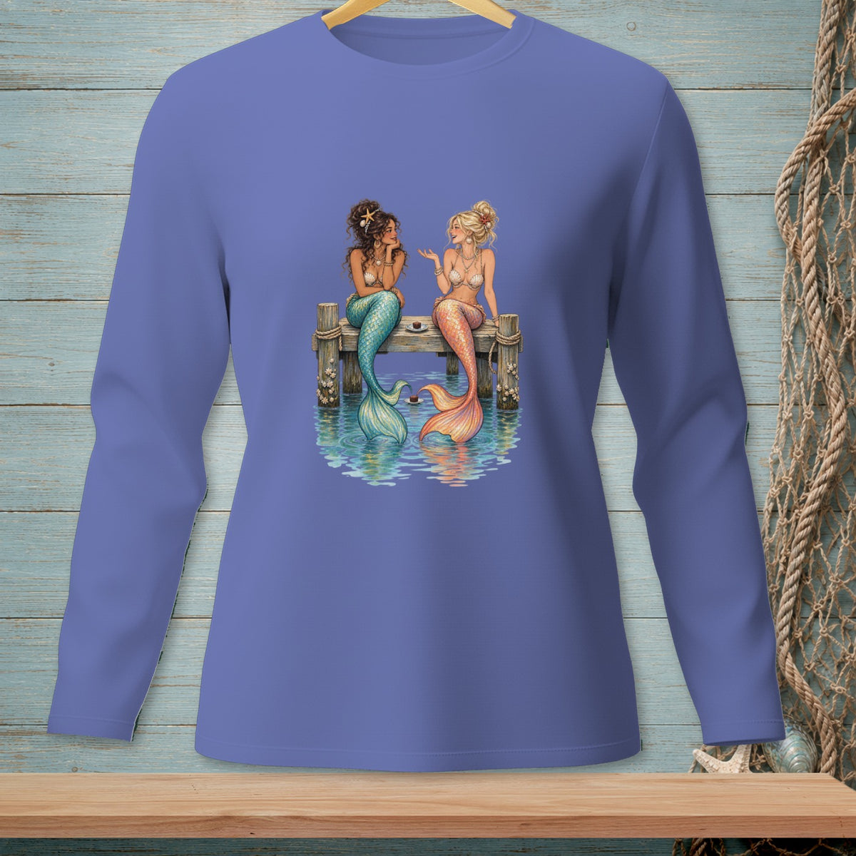 Two mermaids with colorful tails sit on a wooden pier talking.