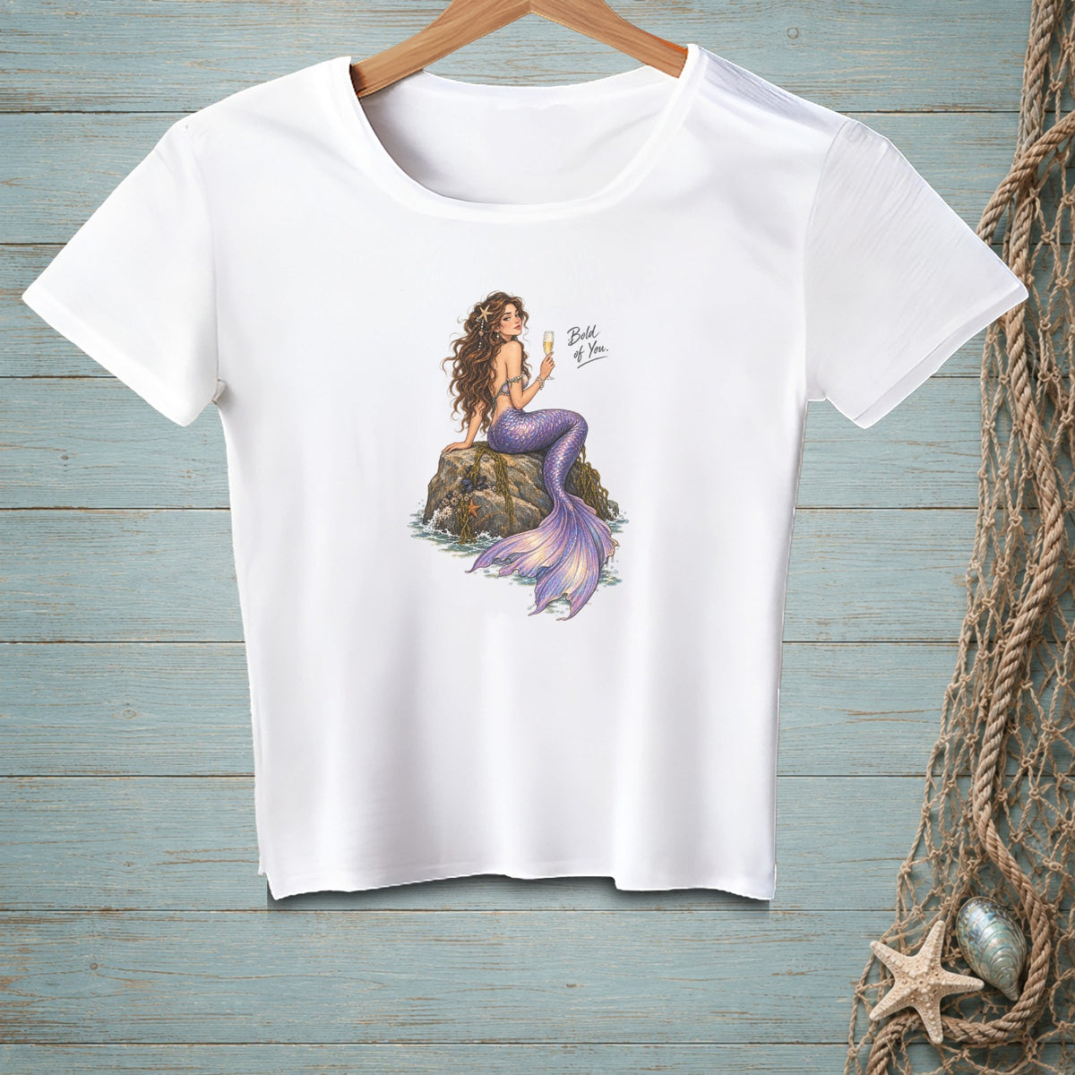 White t-shirt with a mermaid holding a champagne flute and text "Bold of You."