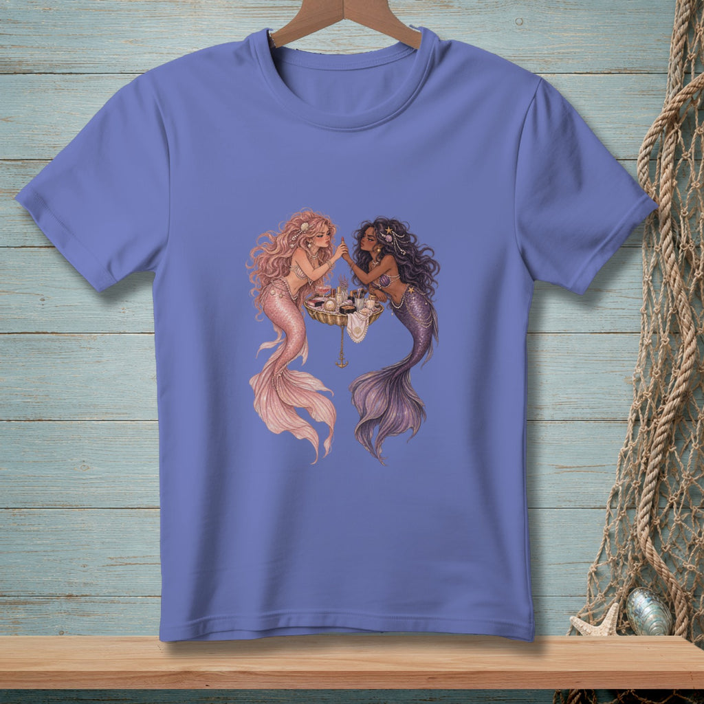 Two mermaids apply makeup at a vanity, one with pink and one with purple tail.