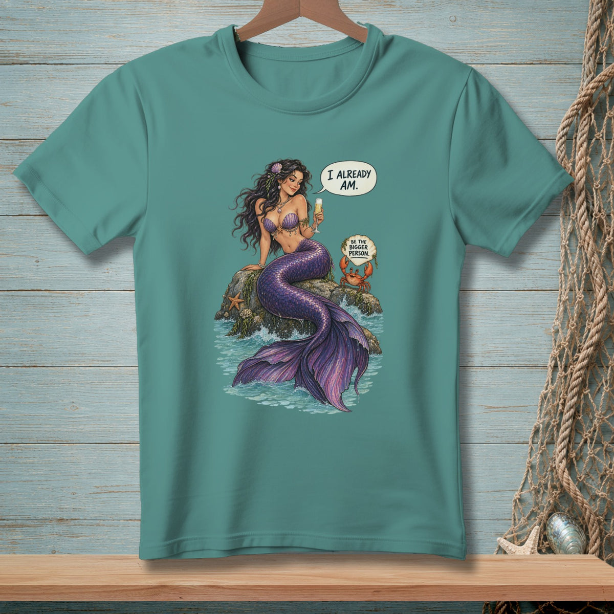 Mermaid with purple tail sitting on rock, holding drink, crab says "Be the bigger person."
