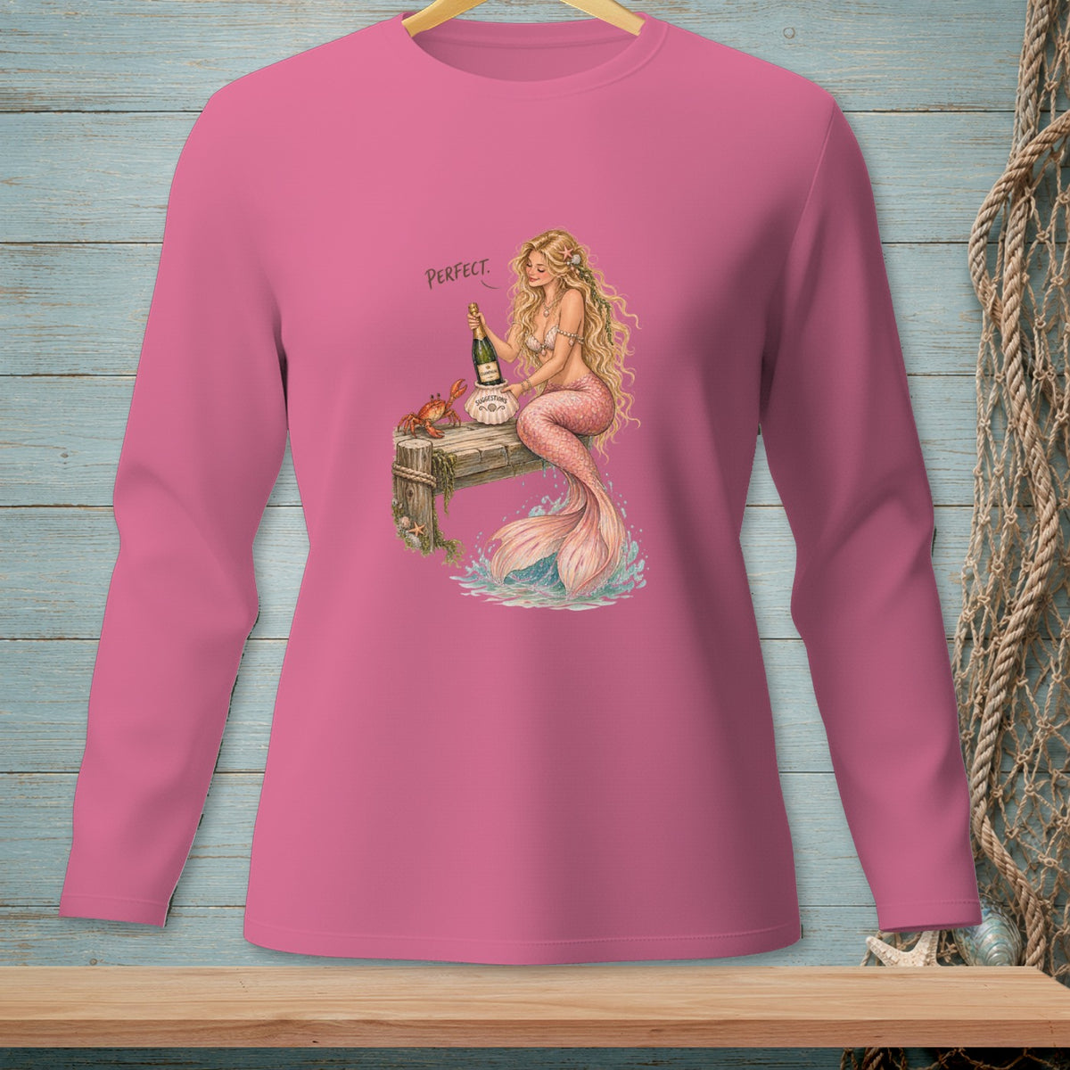 Pink long-sleeved shirt with a mermaid holding champagne and the word "PERFECT".