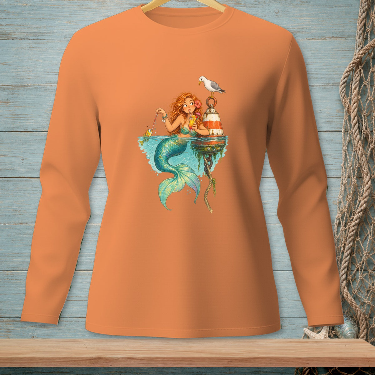 Long-sleeve orange shirt with a graphic of a mermaid fishing by a buoy and a seagull.