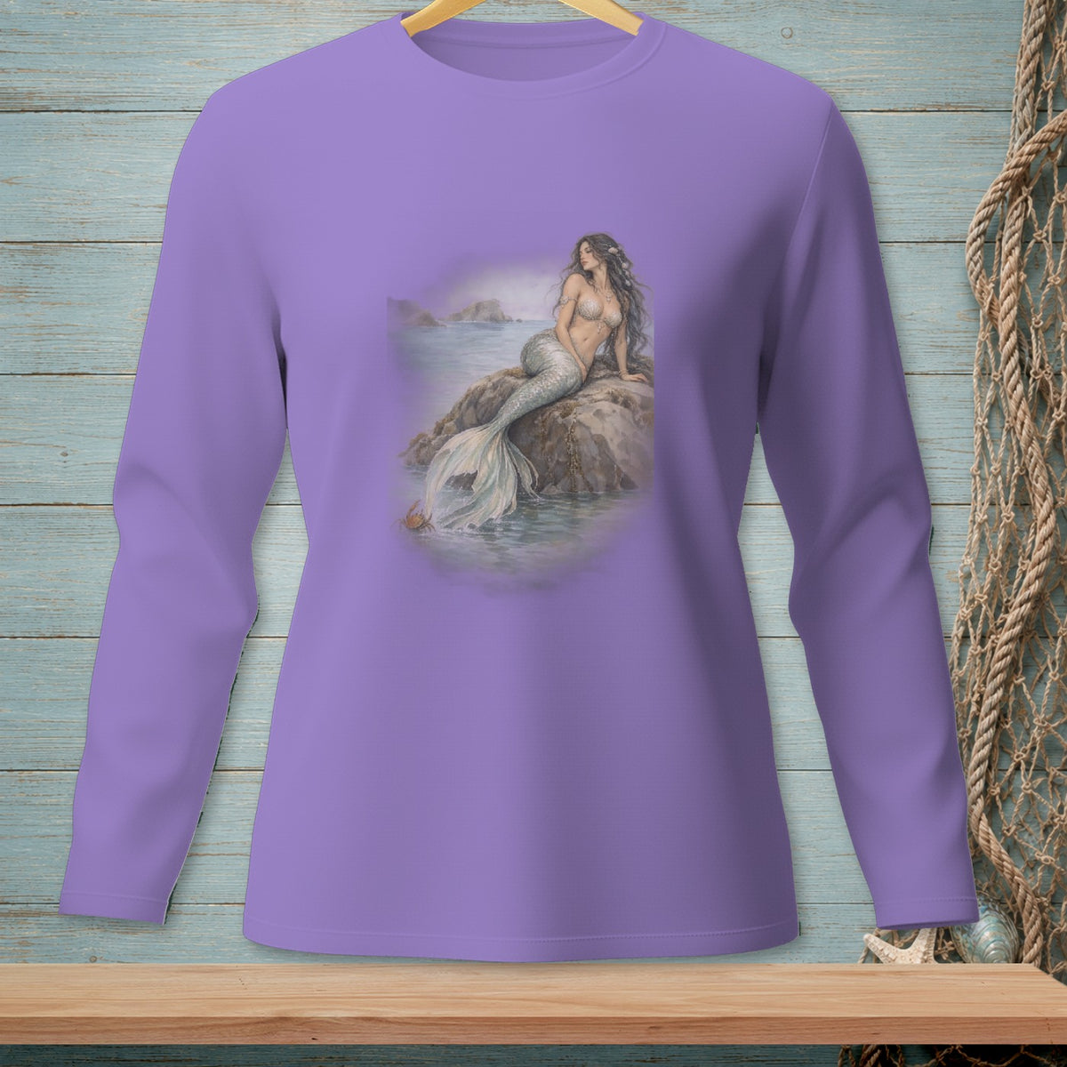 Mermaid sitting on rock by the sea, printed on a lavender long-sleeve shirt.