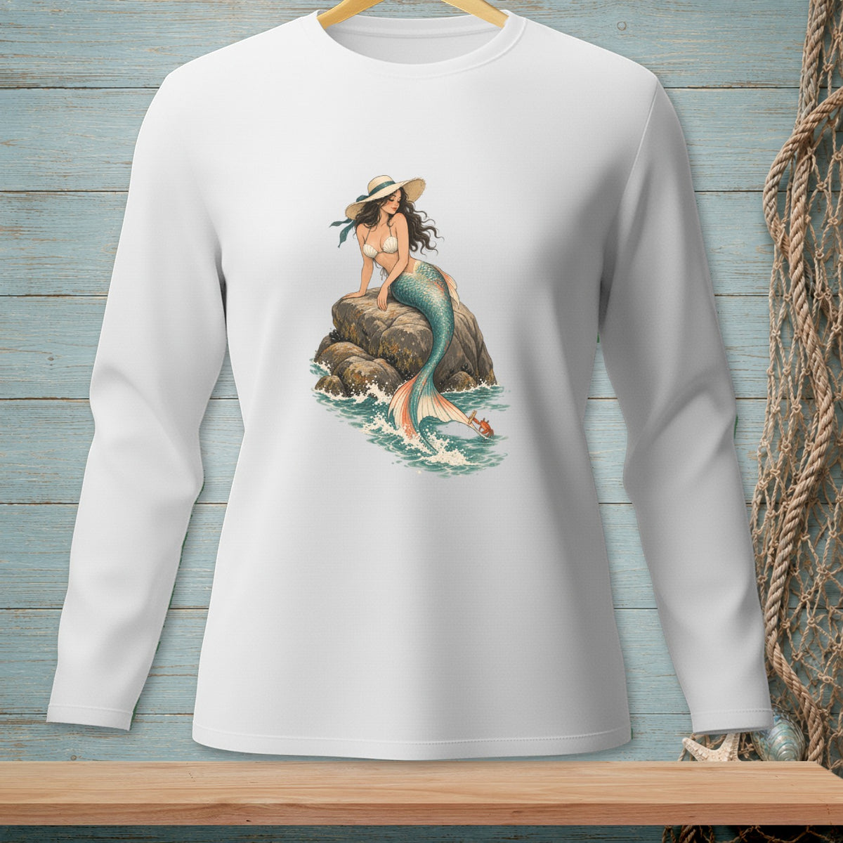 White long-sleeve shirt with a graphic of a mermaid sitting on a rock in the ocean.
