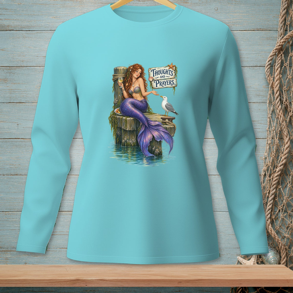 Mermaid with a glass of wine sits on a pier next to a seagull, with text "Thoughts and Prayers."