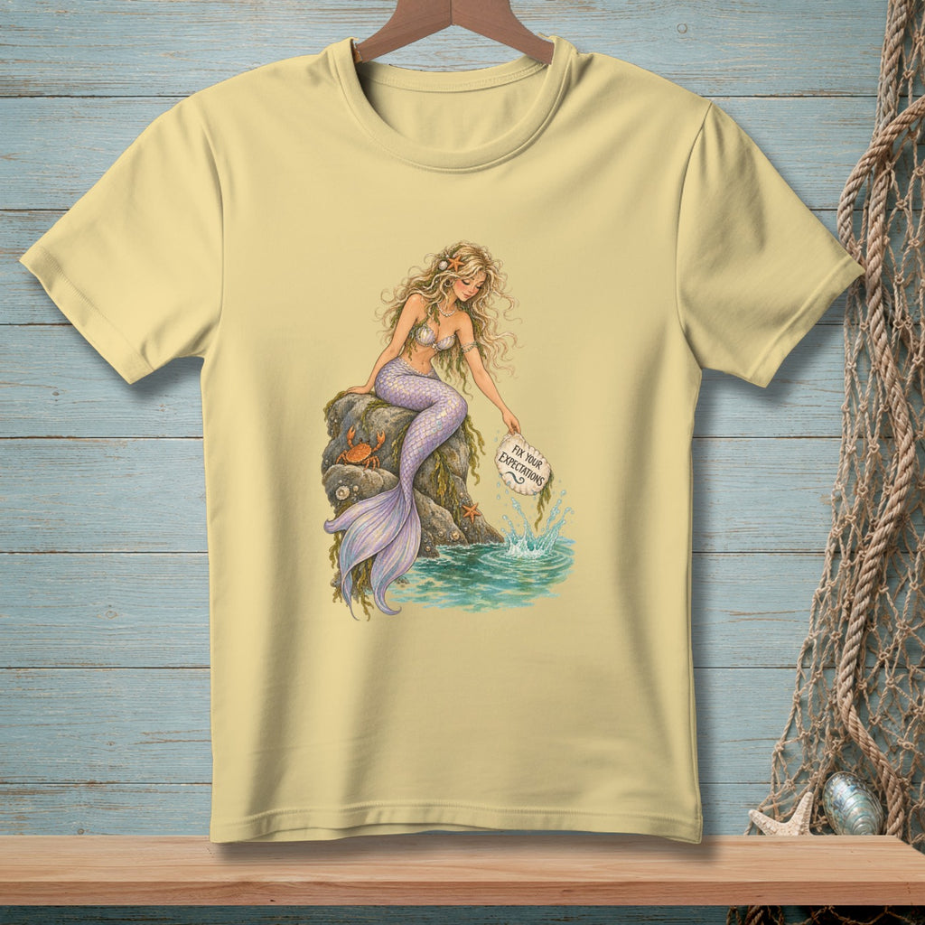 Yellow t-shirt with a mermaid sitting on a rock, holding a sign that says "Fix Your Expectations".