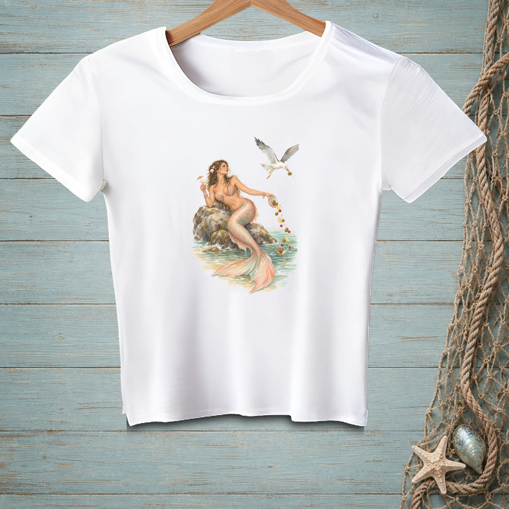 White t-shirt with watercolor mermaid feeding a seagull from a bowl of fruit.