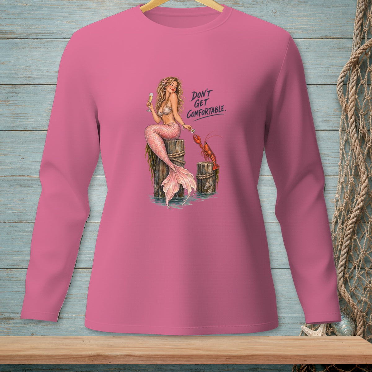 Pink long-sleeve shirt with mermaid and lobster graphic and text "DON'T GET COMFORTABLE."