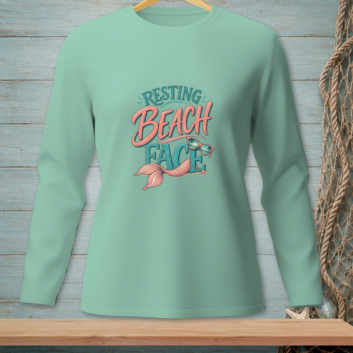 Long-sleeve shirt with "Resting Beach Face" text, sunglasses, and mermaid tail.