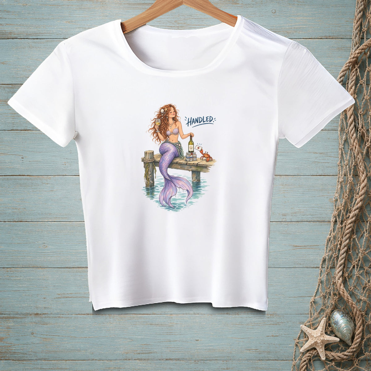 White t-shirt with a mermaid sitting on a dock holding wine and text "Handled".
