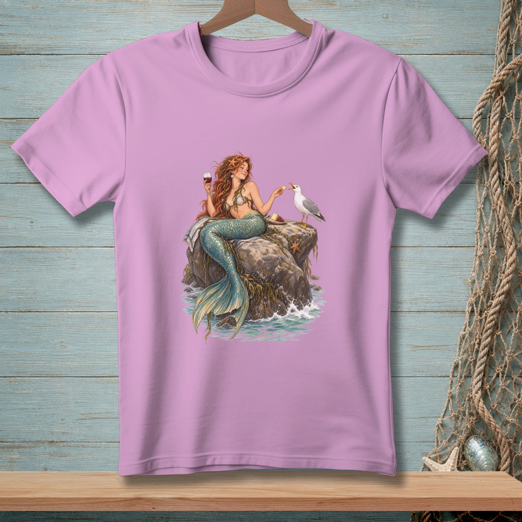 Mermaid with red hair sits on a rock, holding a wine glass, feeding a seagull.
