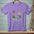 Purple t-shirt with two mermaids sitting on rocks with water.