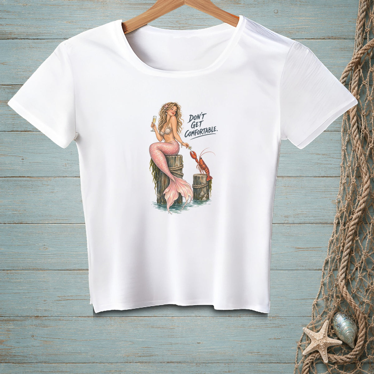 White t-shirt with mermaid, lobster, and text "DON'T GET COMFORTABLE."