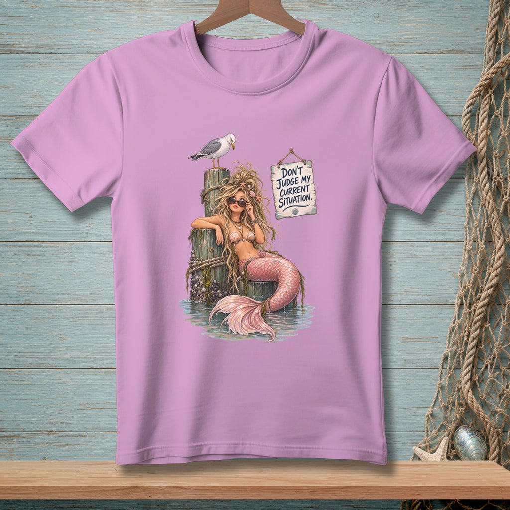 Pink t-shirt with illustration of a mermaid and seagull on a pier, and text sign.