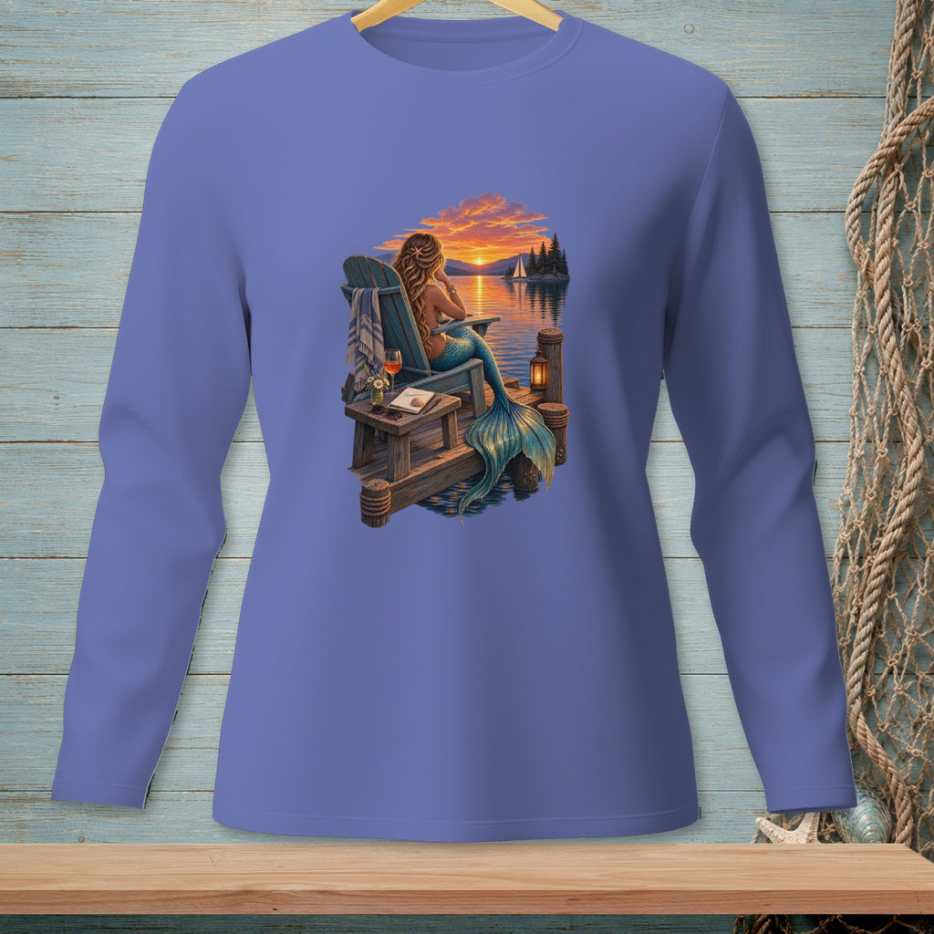 Mermaid on dock at sunset with sailboat and lighthouse.