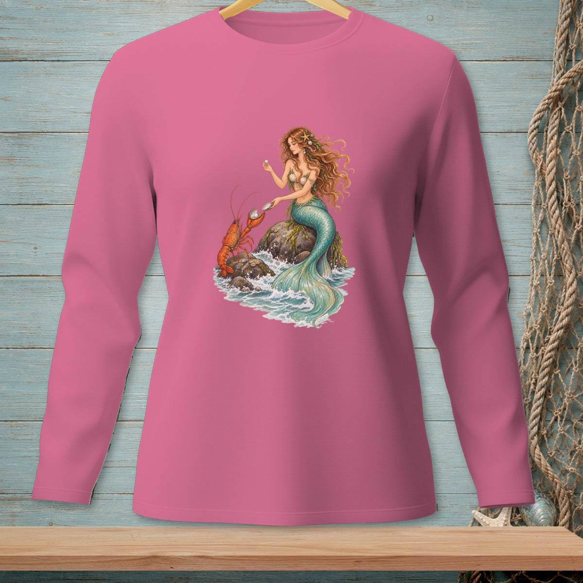 Long sleeve pink shirt with a mermaid and lobster graphic on a rock.