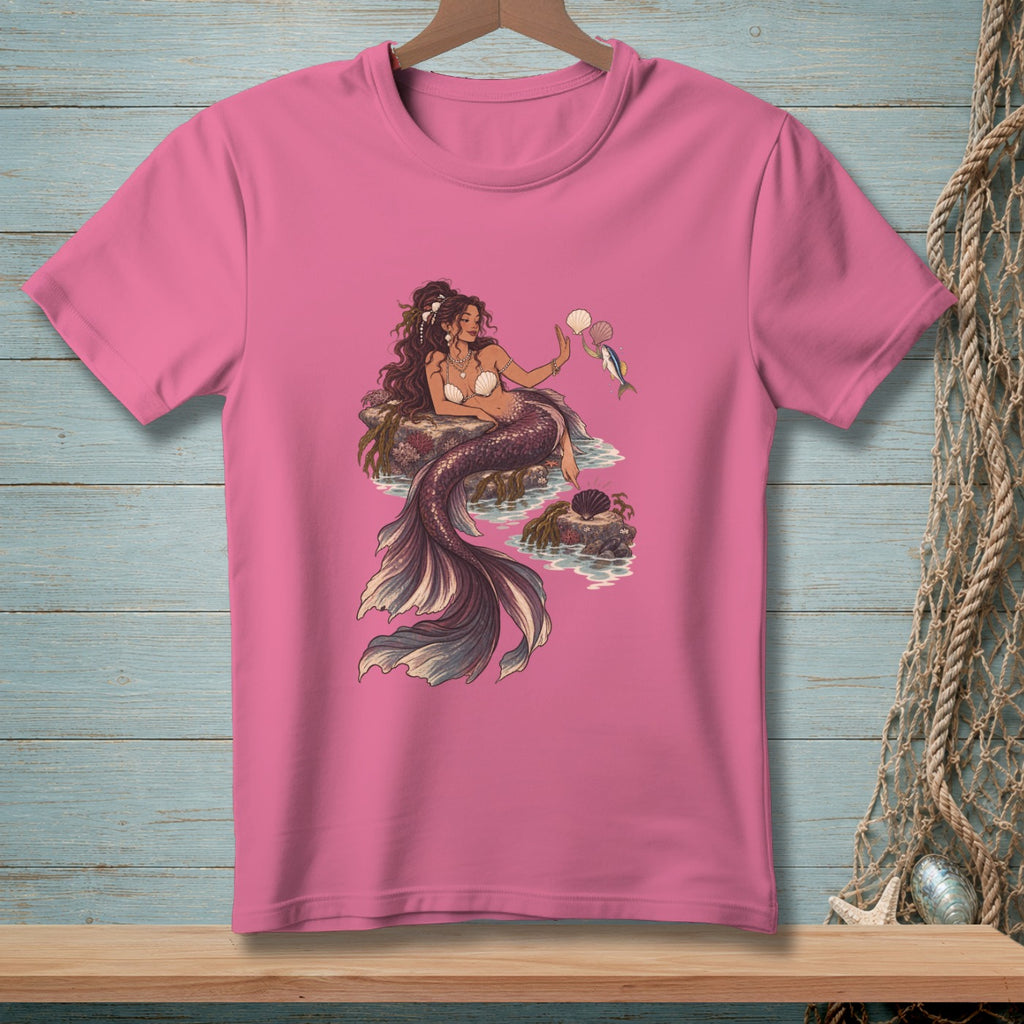 Mermaid holding a shell and a fish, sitting on rocks in the ocean.