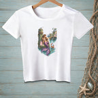 White t-shirt featuring a mermaid with a purple tail, sitting on a dock with a shopping bag.