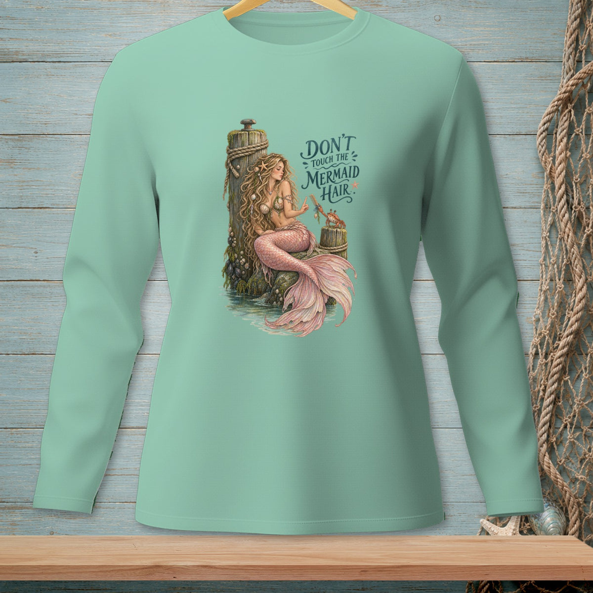 Mermaid with pink tail sitting on rocks, text "Don't touch the mermaid hair".