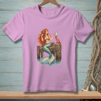 Mermaid holding mirror with crab on wooden pier, printed on a pink t-shirt.