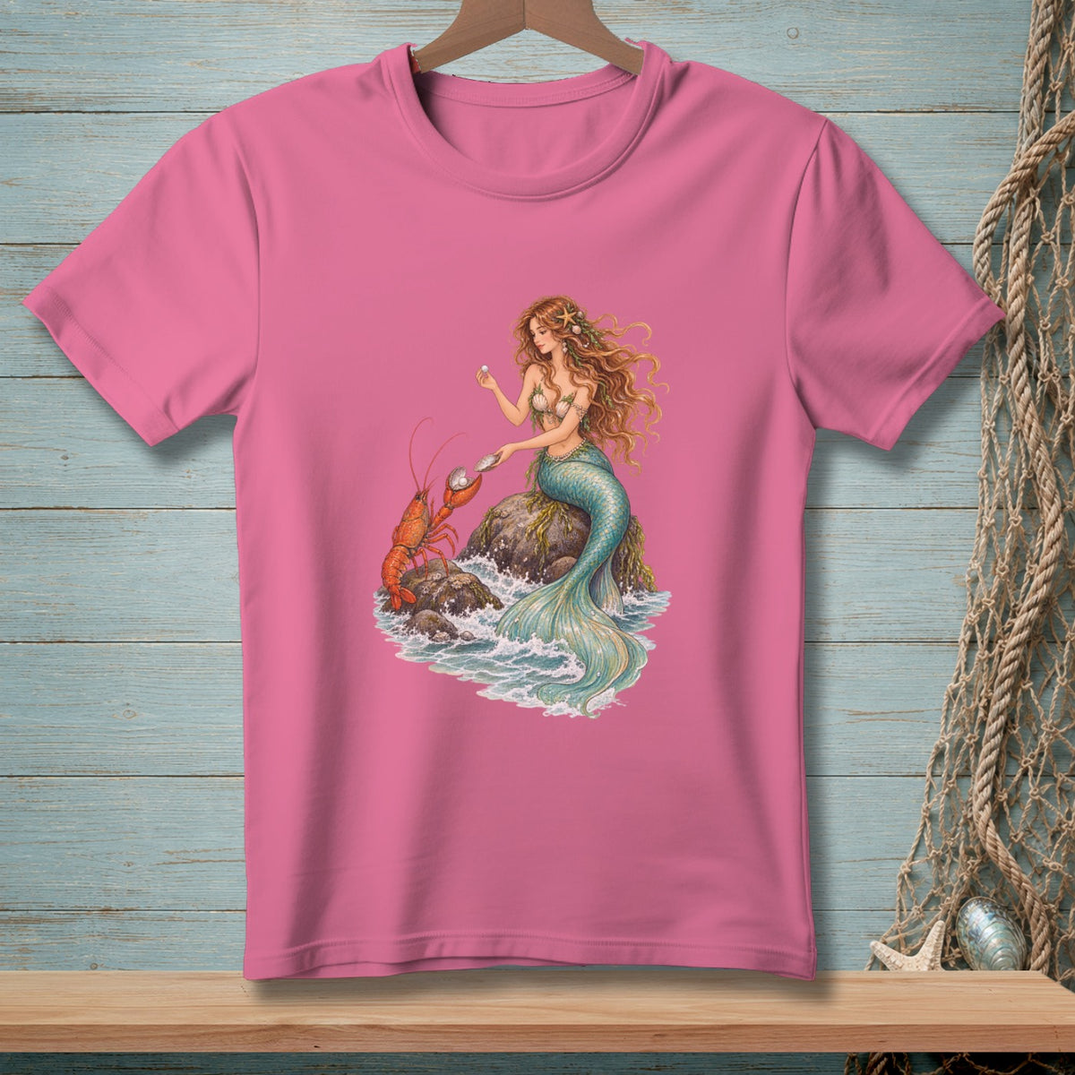 Pink t-shirt with illustration of a mermaid holding a pearl next to a lobster.