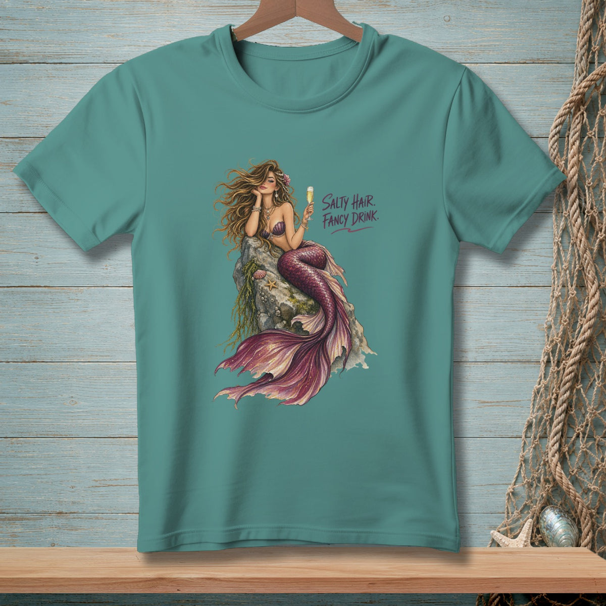 Teal t-shirt with illustration of a mermaid on a rock holding a drink, "Salty Hair. Fancy Drink."