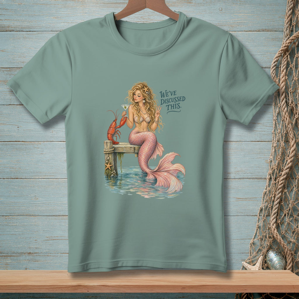 Mermaid with lobster on pier, holding martini, text says "We've discussed this."
