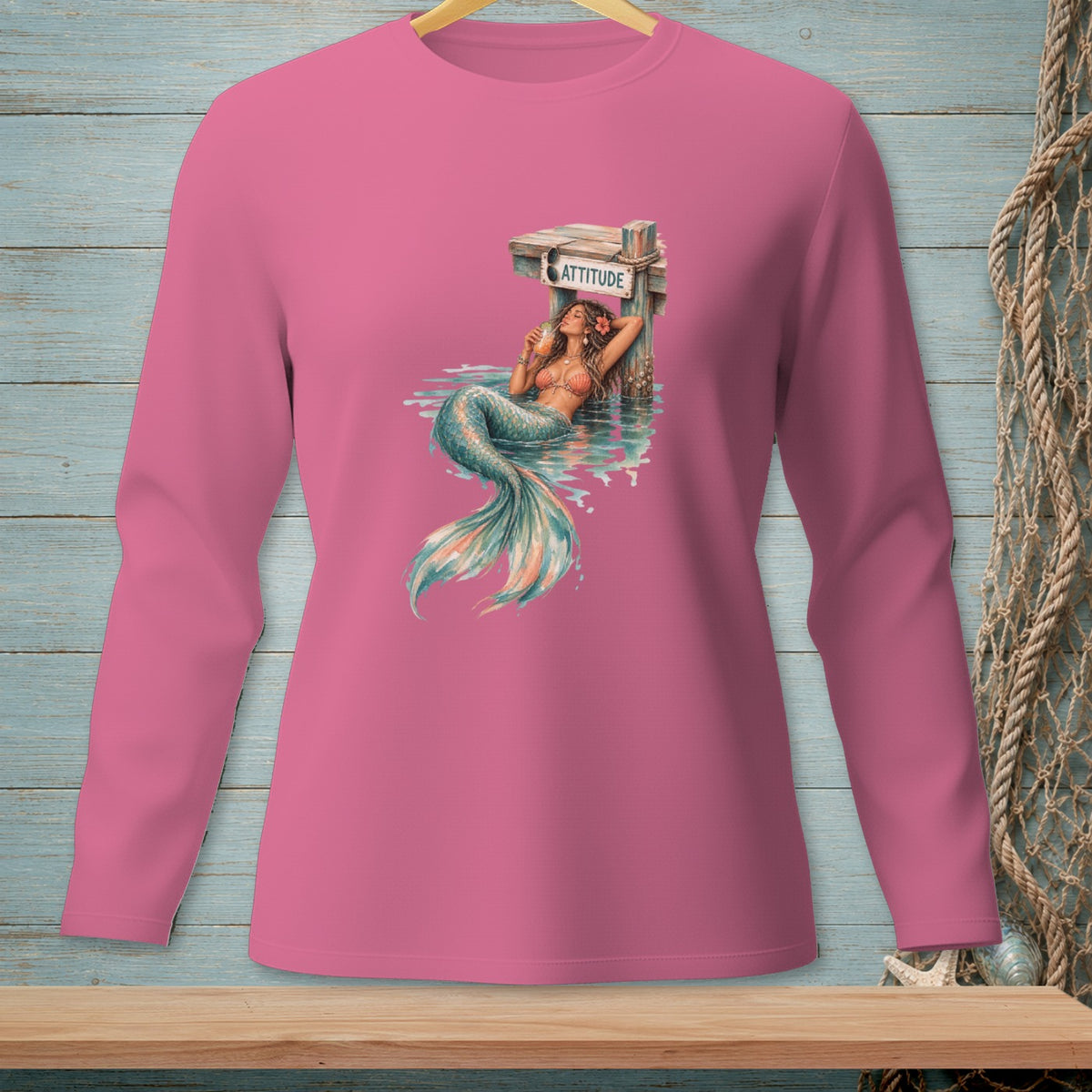 Pink long-sleeve shirt with a mermaid graphic and the word "ATTITUDE" on a sign.