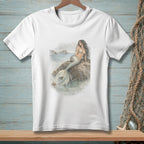 White t-shirt with a watercolor illustration of a mermaid on a rock.