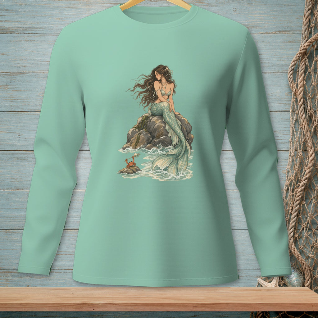 Mermaid sitting on rock with crab at her feet, light teal long-sleeve shirt.