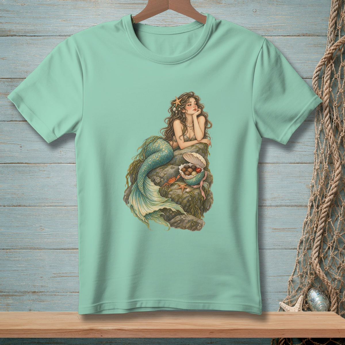 Mermaid resting on rocks with a treasure chest of pearls and shells.