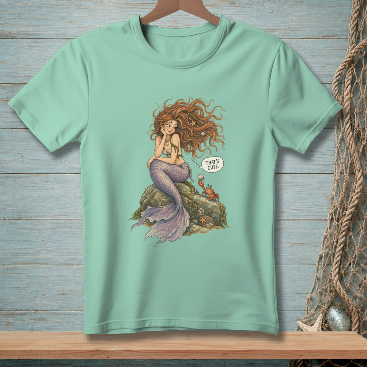 Mermaid sitting on rock with crab, speech bubble says "That's cute."