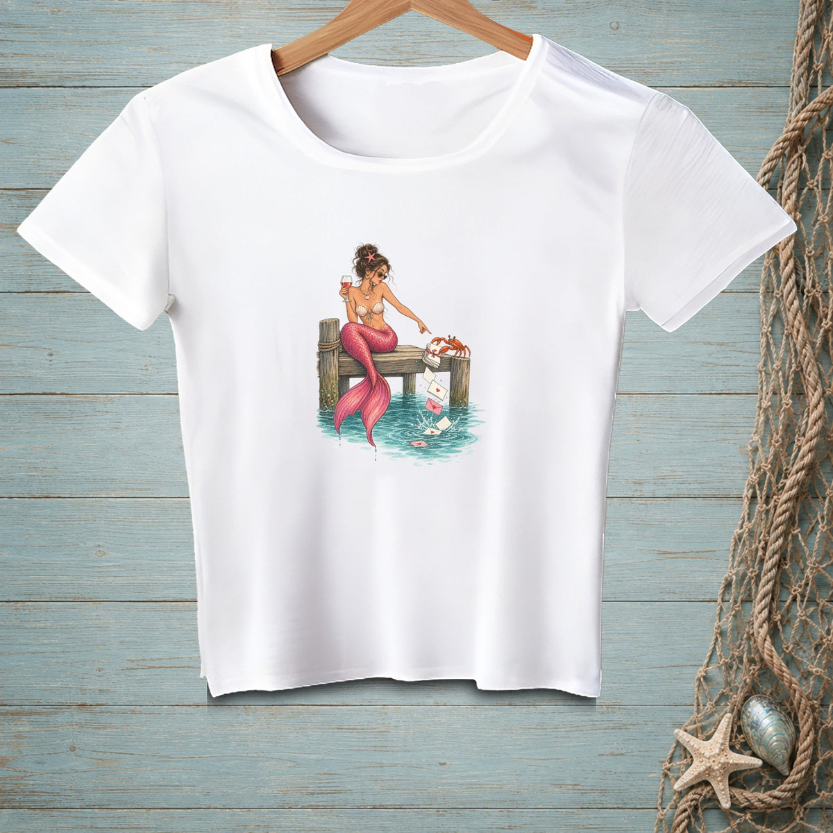 Mermaid sitting on a dock with a crab and floating letters.