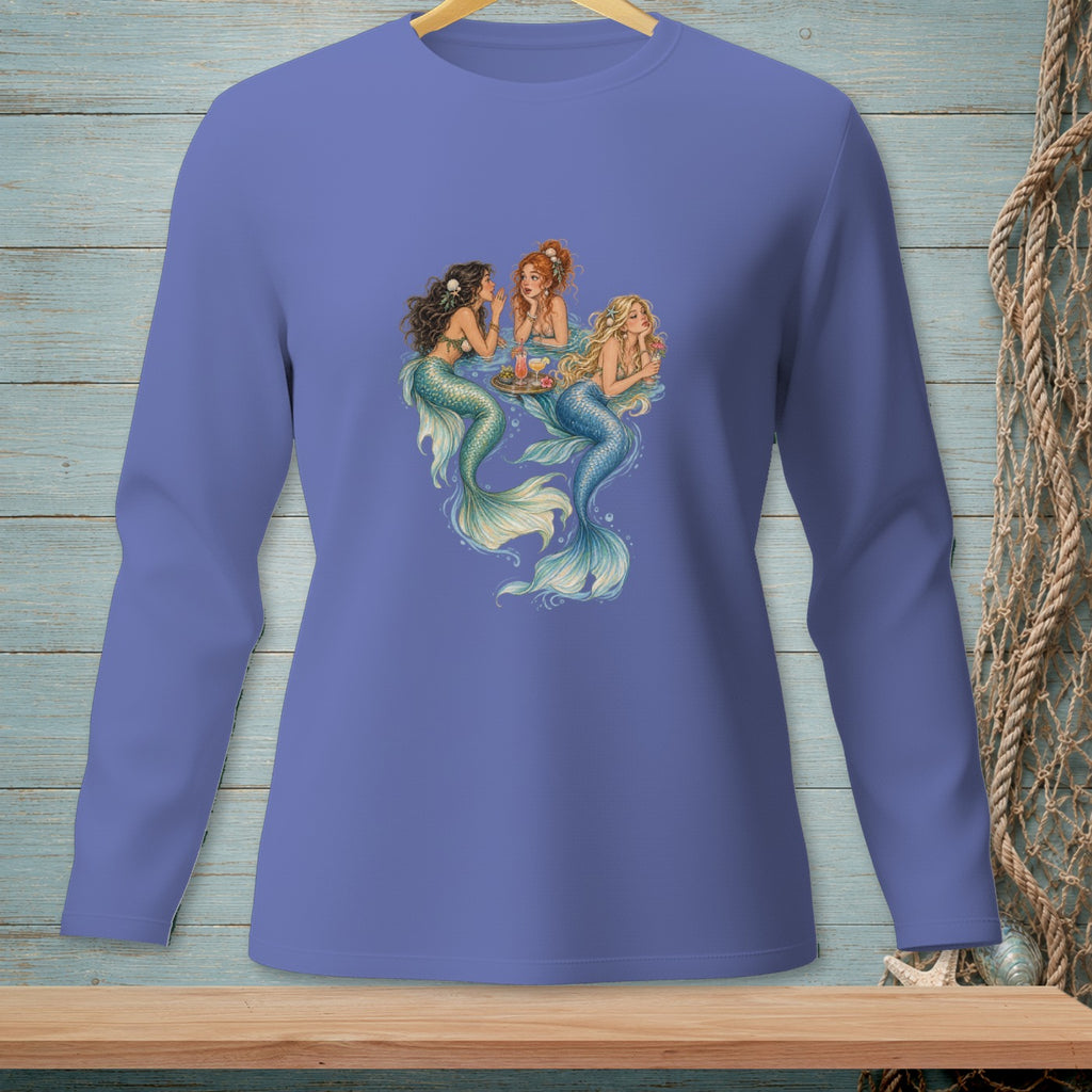 Three mermaids with colorful tails relax and share drinks around a floating tray.