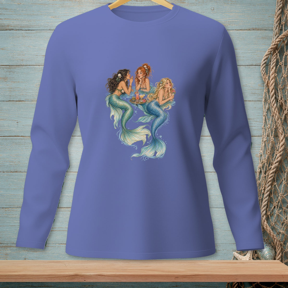 Three mermaids with colorful tails relax and share drinks around a floating tray.