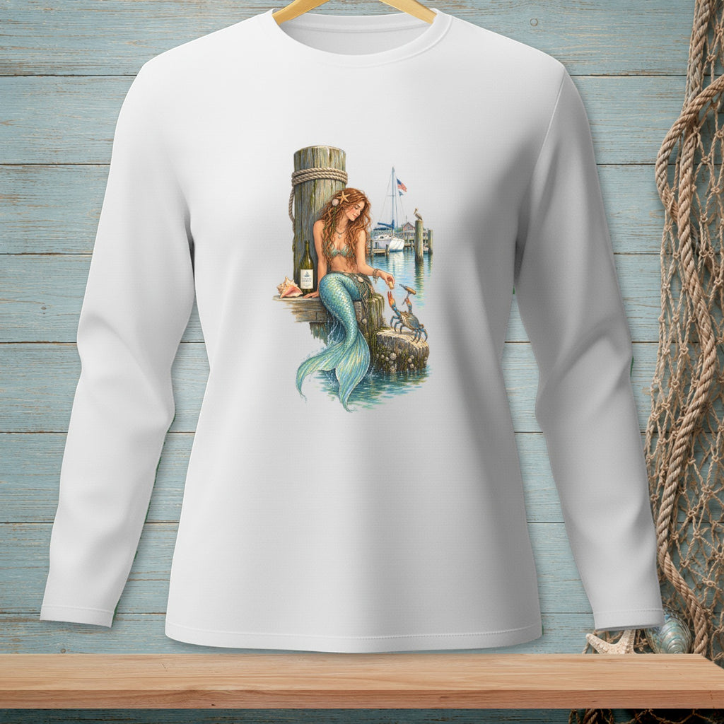 Mermaid on a dock feeding a crab, with a sailboat in the background.