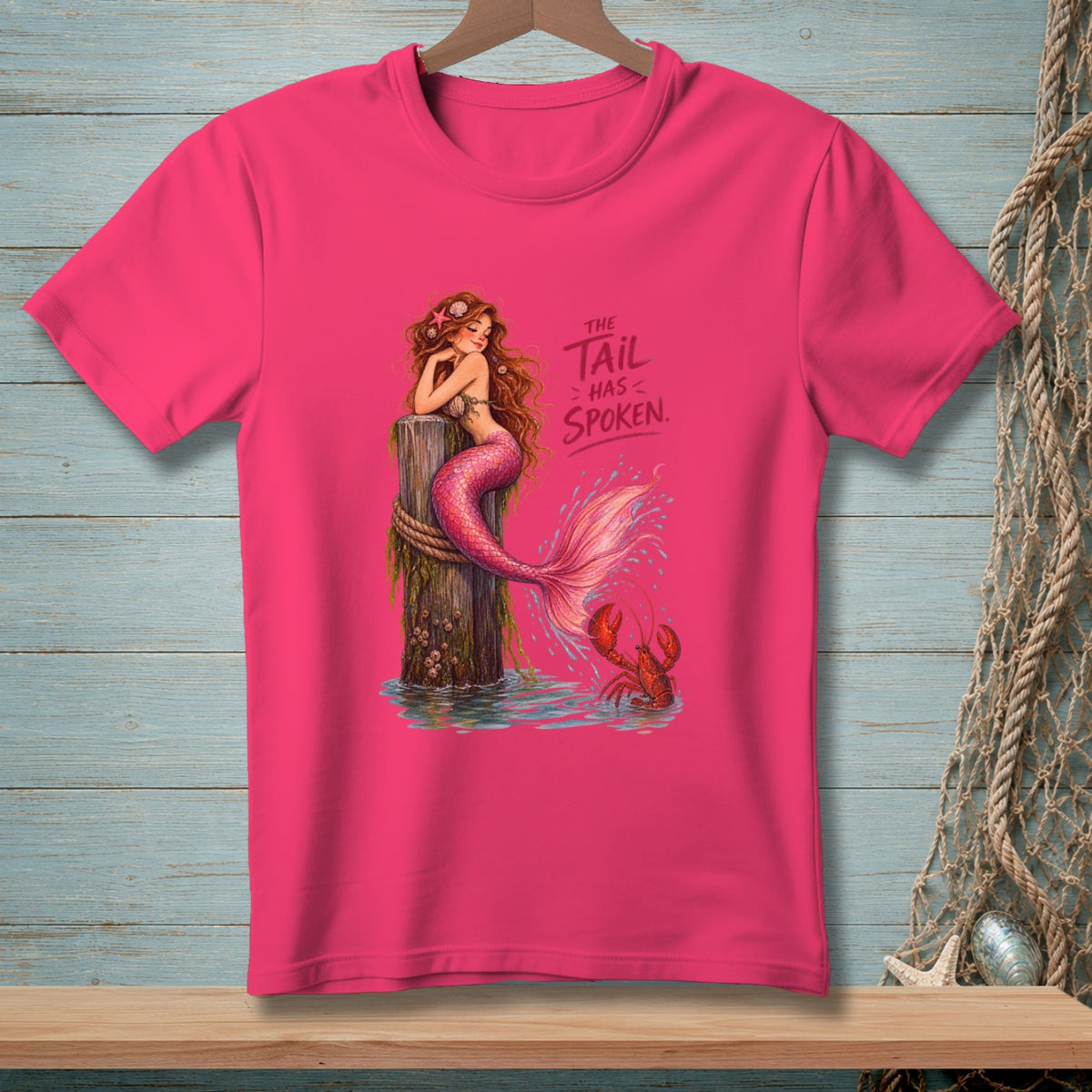 Pink t-shirt with a mermaid on a post and text: The Tail Has Spoken.