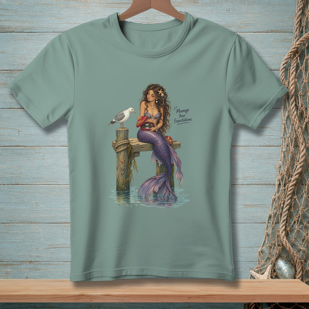 Mermaid on dock with seagull holding candy box, text "Manage Your Expectations."