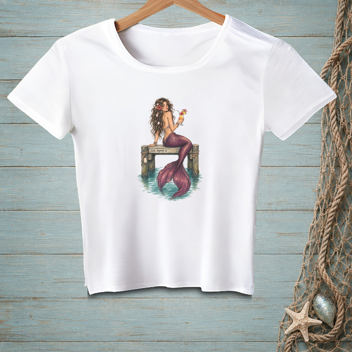 White t-shirt with mermaid holding a cocktail on a dock, text "Cute Anyway".