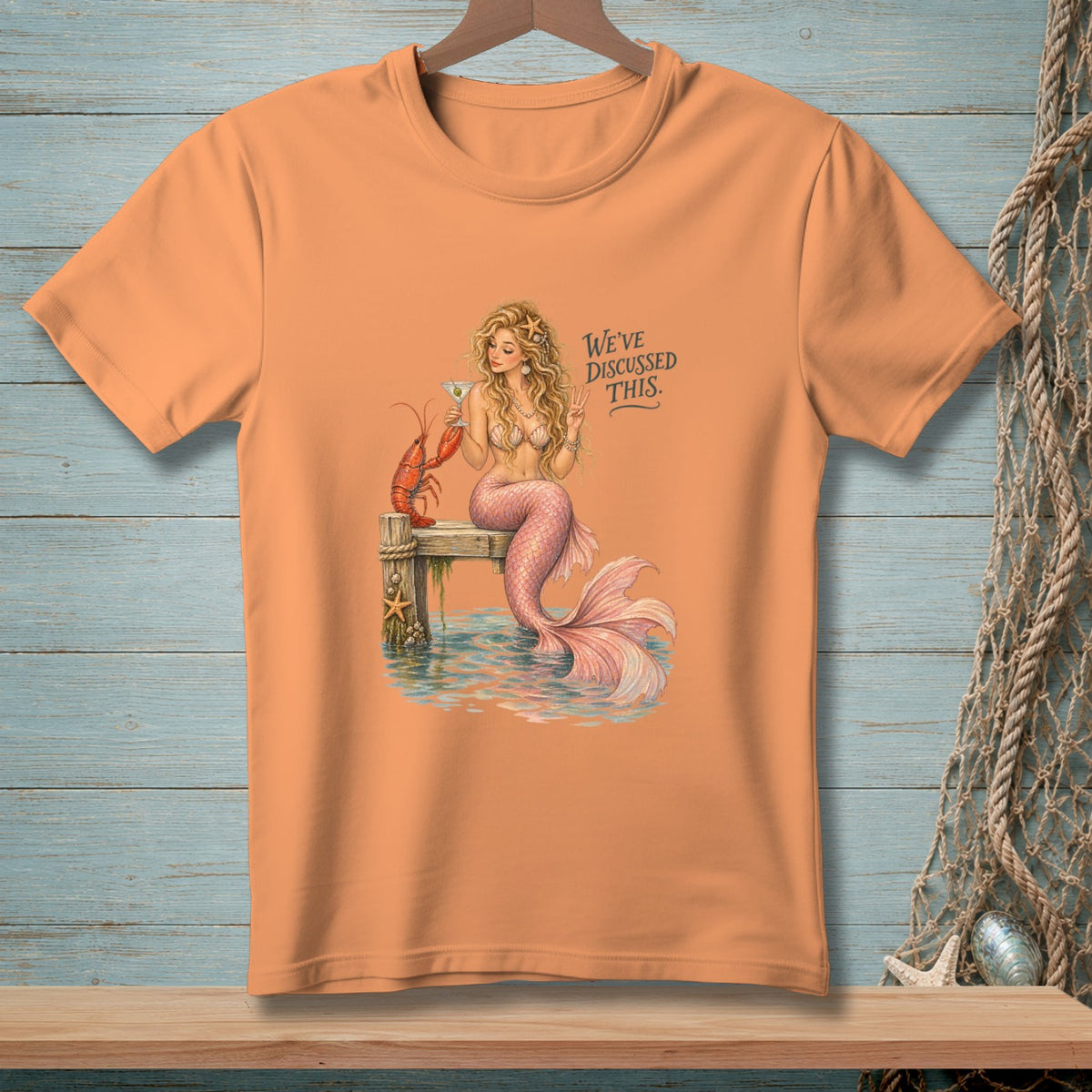 Peach t-shirt with mermaid, lobster, and text "We've discussed this."