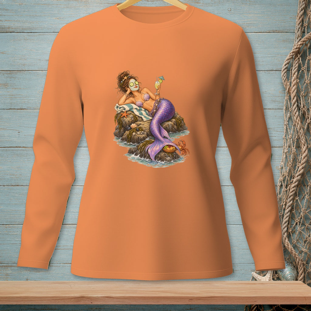 Orange long-sleeve shirt featuring a mermaid relaxing on rocks with a drink and face mask.