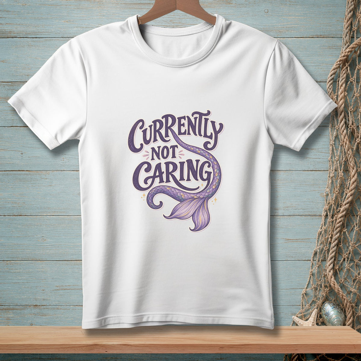 White t-shirt with purple text "Currently Not Caring" and a mermaid tail graphic.