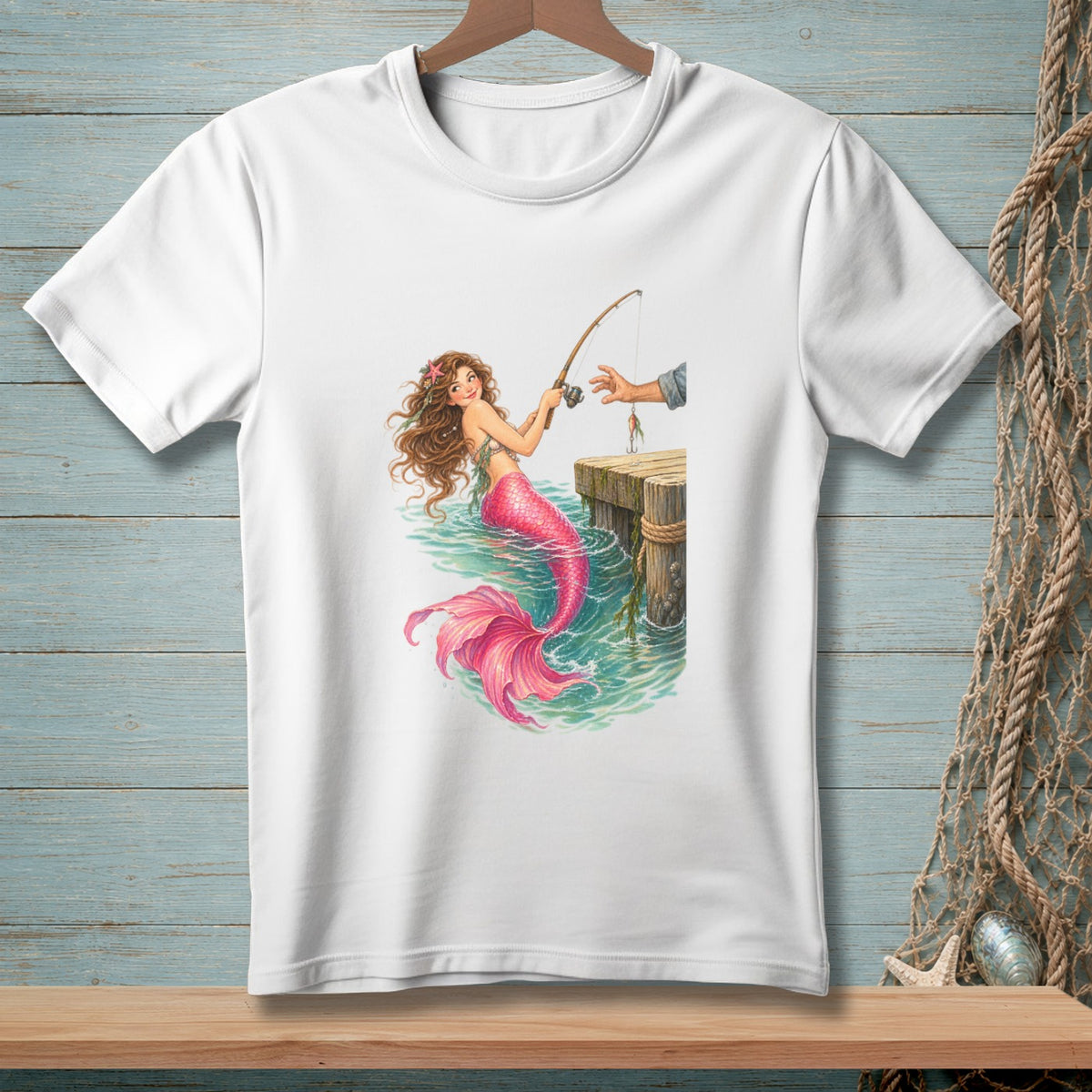 White t-shirt featuring a mermaid fishing from a wooden pier with a human hand.